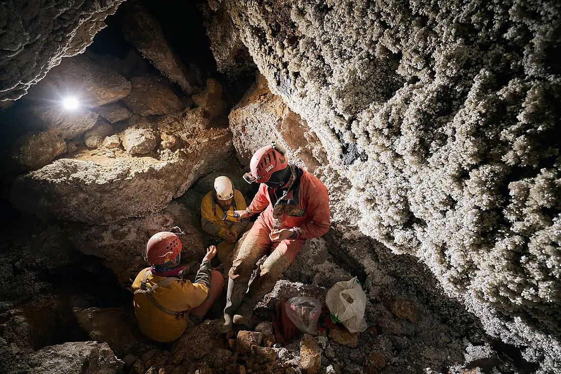 Cavers at the wall covered with aragonite crystals in Skalarjevo brezno 2021